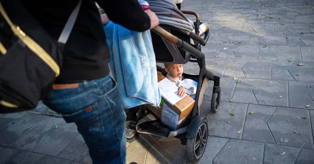 hátizsákos nő babakocsit tol, benne alszik a gyerek