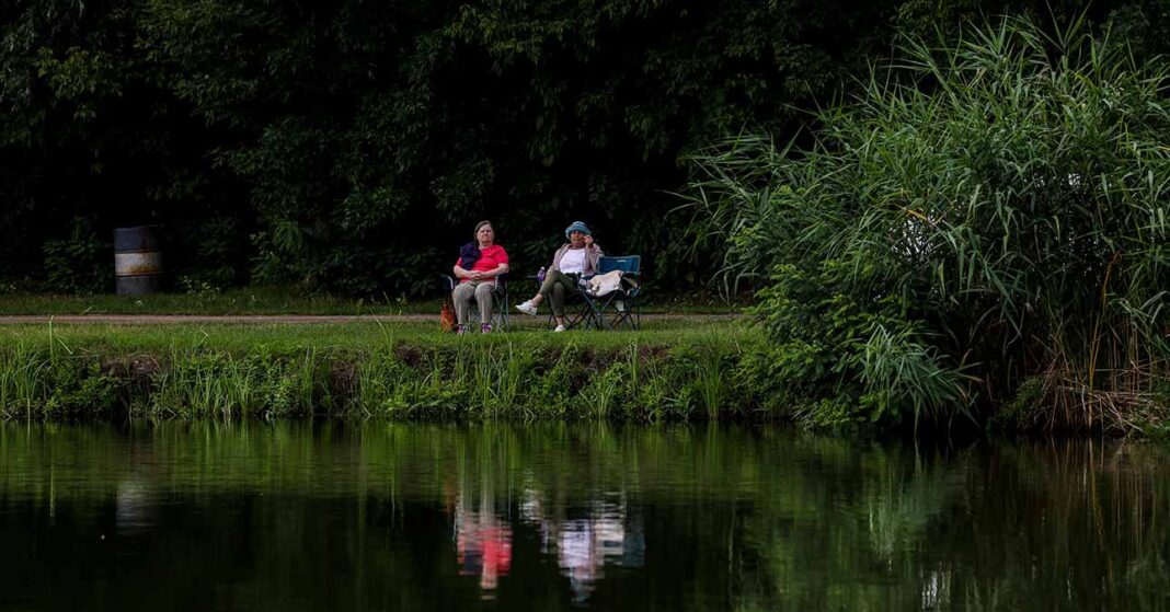 nyugdíjasok padon, zöldövezetben, tóparton