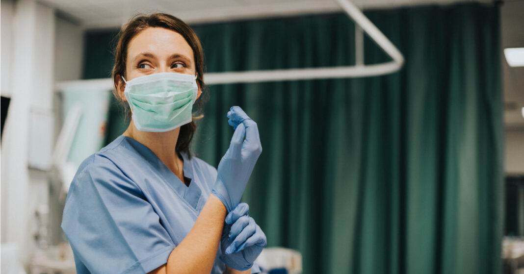Female nurse with a mask putting on gloves ápoló fizetés
