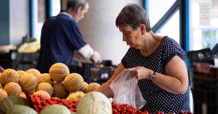 nyugdíjas gyümölcsöt válogat a piacon