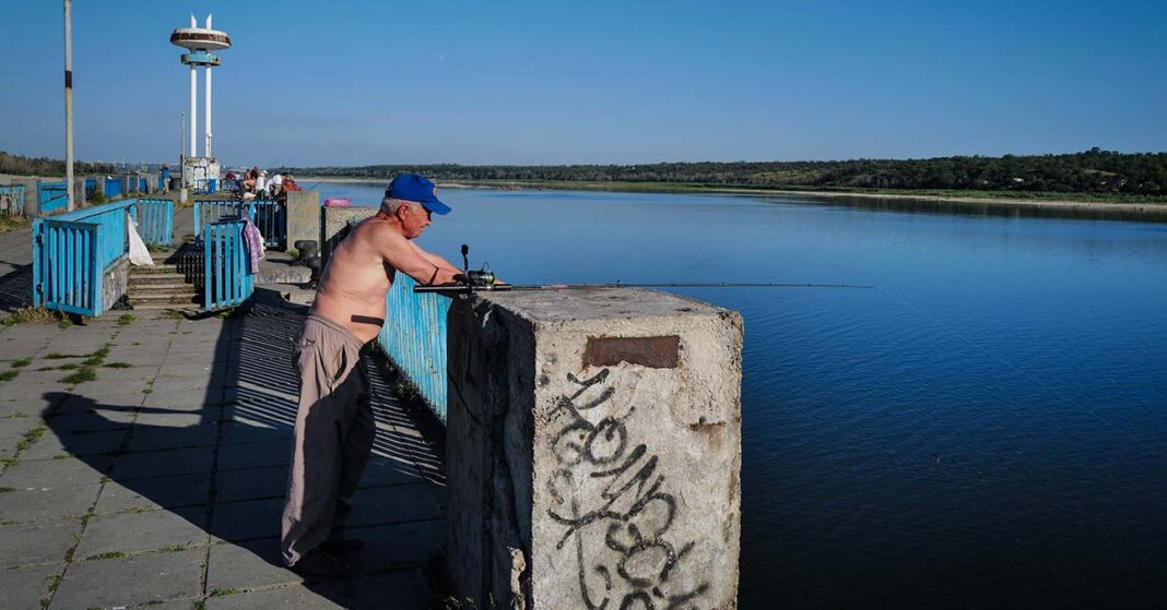 félmeztelen horgász a vízparton sildes sapiban