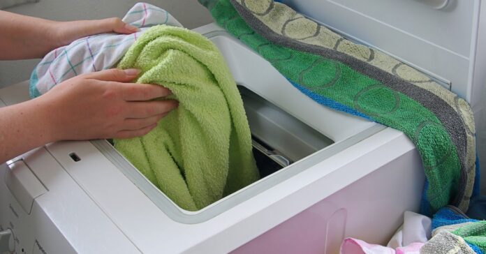 mosógép nő a mosógépből veszi ki a tiszta ruhákat