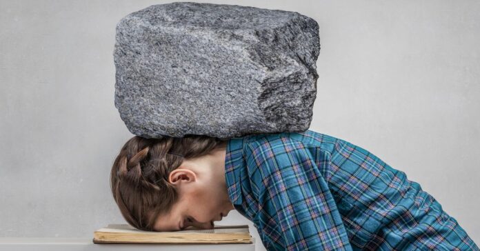 fiatal lány arccal könyvre dőlve, nyakán ás vállán nagy szürke kő