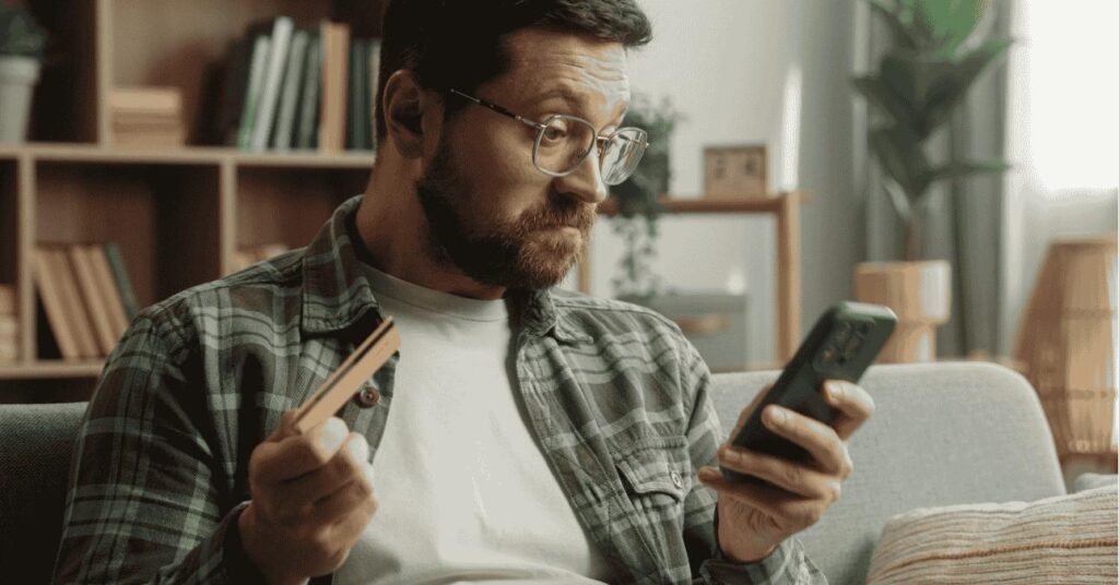 férfi nézi a telefonján az internetes csalókat