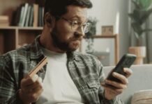 férfi nézi a telefonján az internetes csalókat
