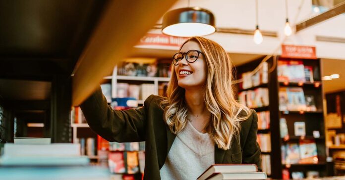 konyvesboltban Fiatal, szőke nő válogat a könyvesboltban