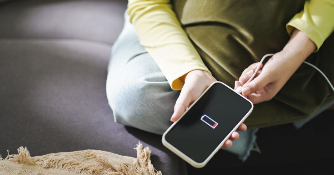 női kézben okostelefon töltőre csatlakoztatva