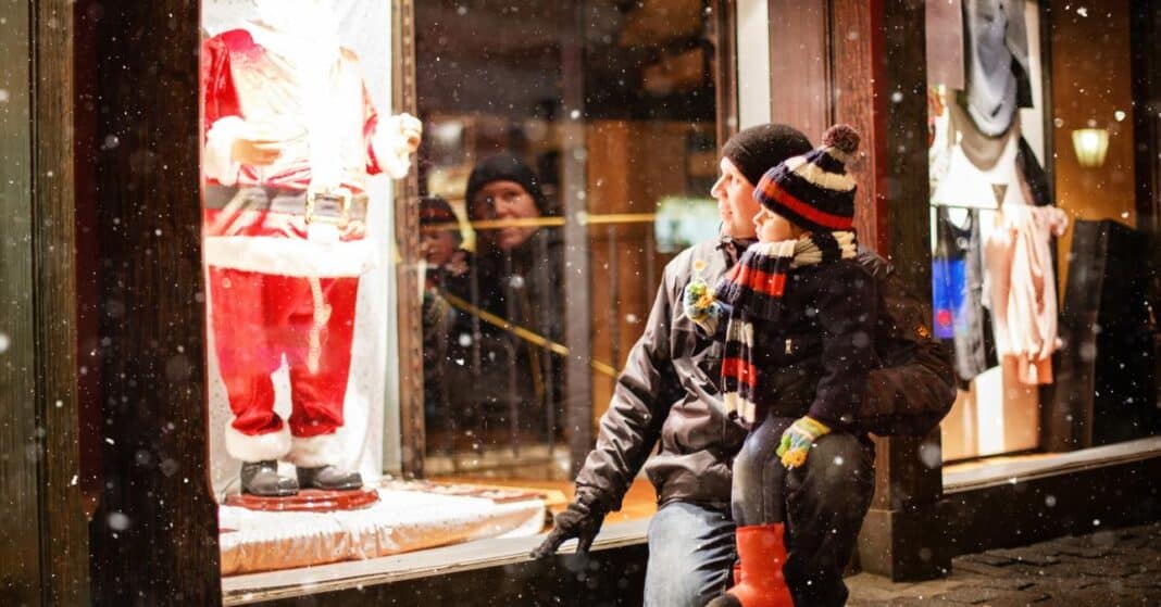 Egy apuka a gyermekével egy kirakatot néz télen. A kirakatban egy Télapó.