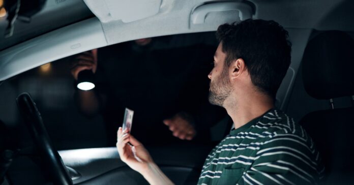 férfi sofőr a jogosítványát nyújtja a rendőrnek