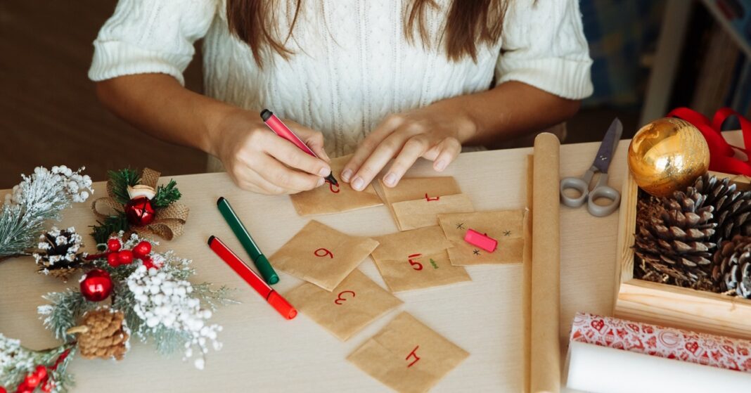 egy női kéz házilag készít adventi kalendáriumot