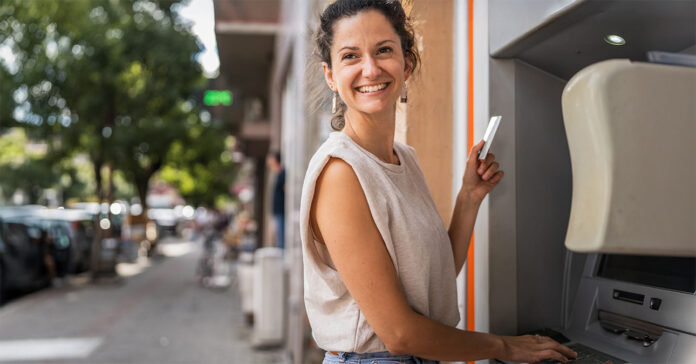 Fiatal nő pénzt vesz föl bankautomatából (ATM) a kártyájával