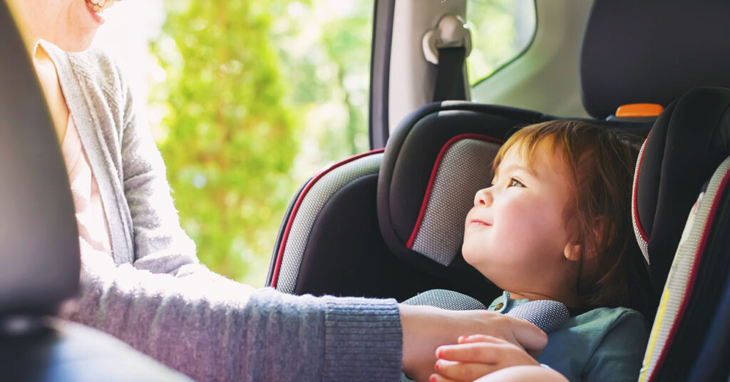 Gyerekülésbe köti be kislányát az anyuka