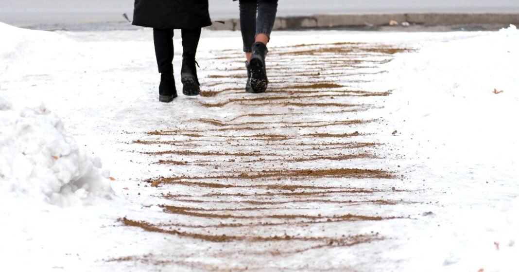 homokkal felszórt jeges úton sétál két nő