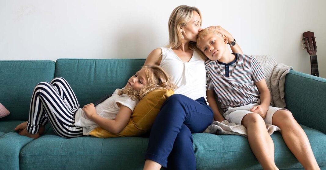 Kétgyermekes anya a kanapén ül a gyerekeivel
