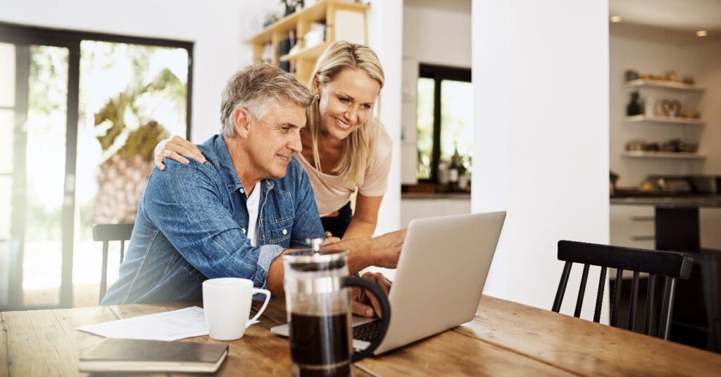 Középkorú pár egy laptop előtt ül az asztalnál.