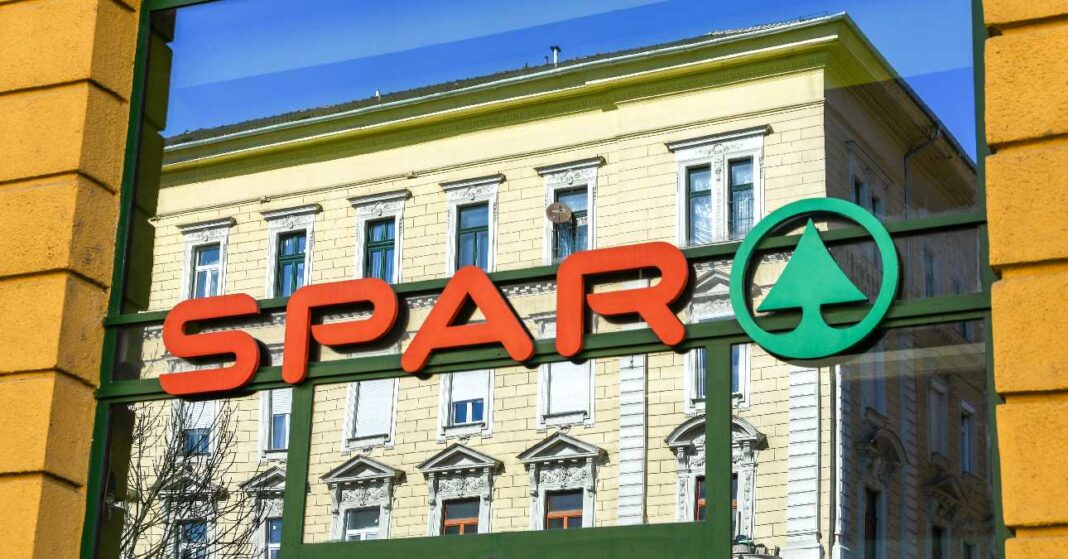 Egy SPAR Budapesten, az üzlet logója az ablakon, szemben lévő épület visszatükröződik a felületen