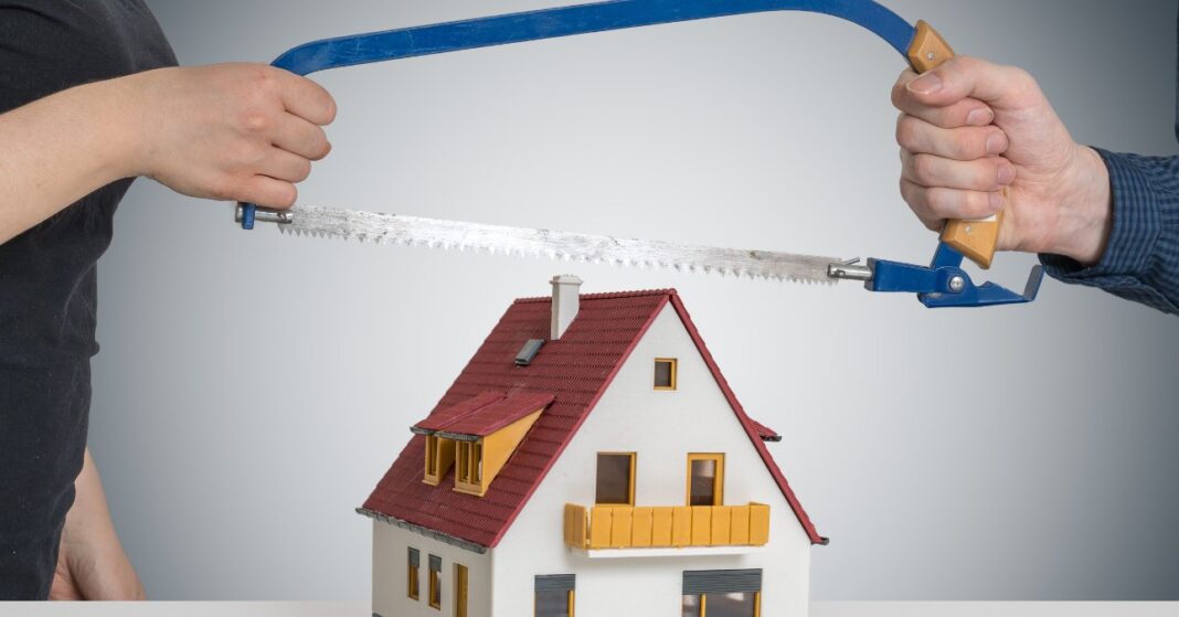 férfi és nő szétfűrészelnek egy makett házat
