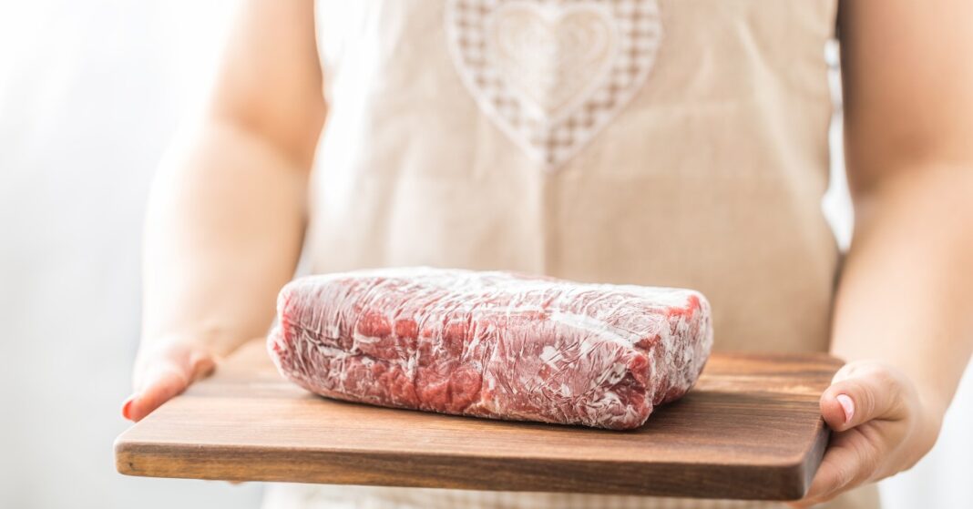 nő kötényben fagyasztott húst tart a kezében