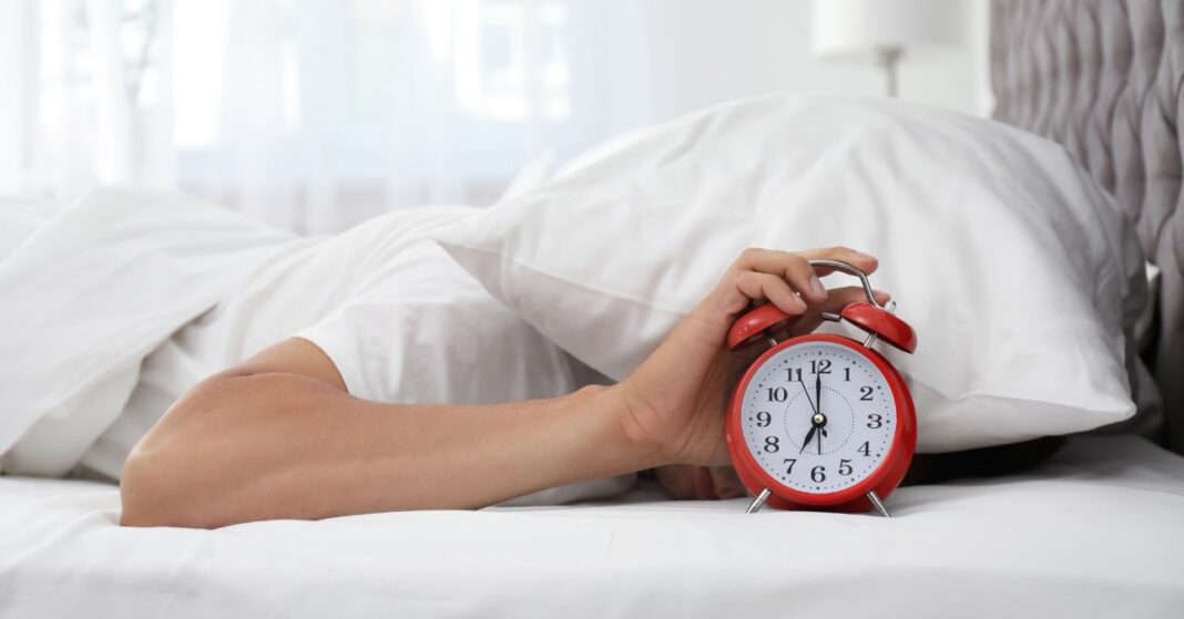 férfi kinyomja az ébresztőt fején párna