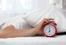 férfi kinyomja az ébresztőt fején párna