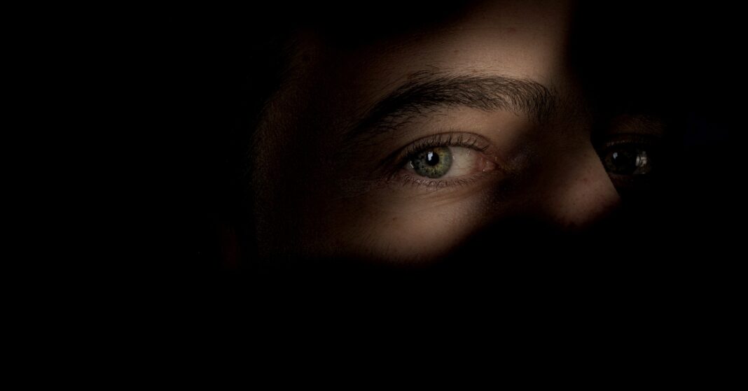 fiatal nő az árnyákban, csak a szeme látszik