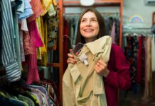 fiatal nő boldogan mutat egy inget a turkálóban