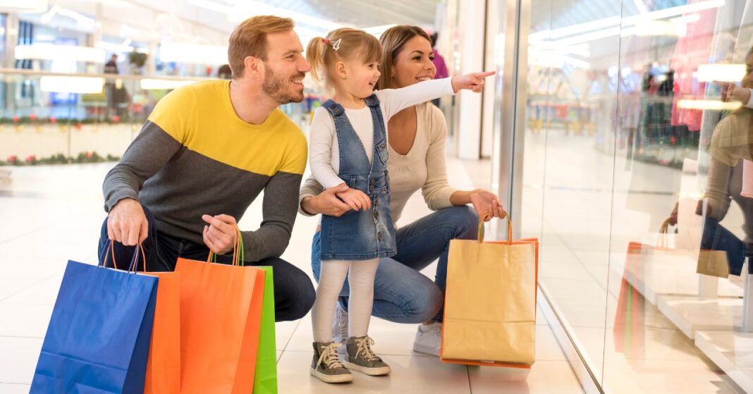 család bevásárlószatyrokkal kirakatot néz