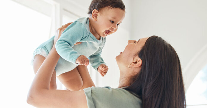 Fiatal édesanya a kisfiával, magasba emeli őt