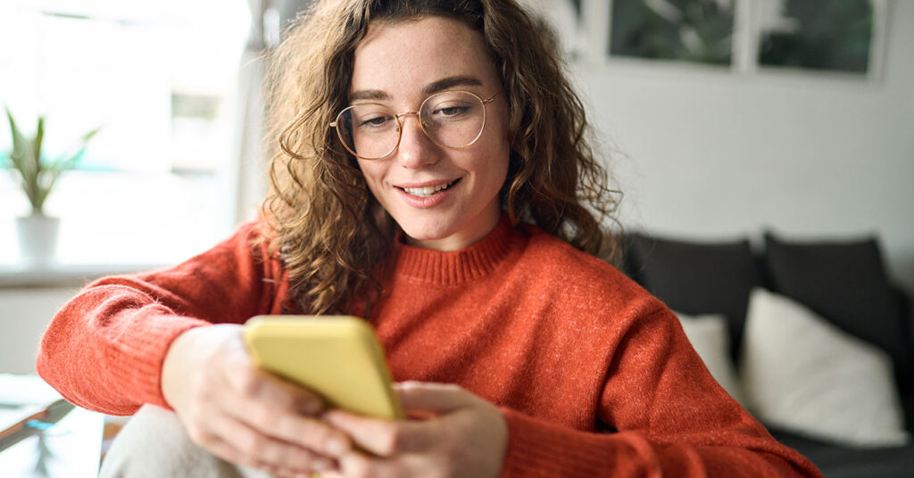 Online vásárlás: fiatal nő okostelefonon rendel valamit az internetről