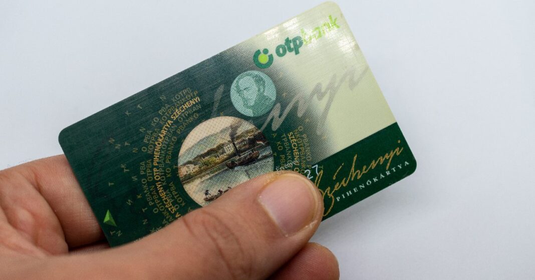 egy férfi kézében SZÉP-kártya, hüvelyujjal letakarva az adatok