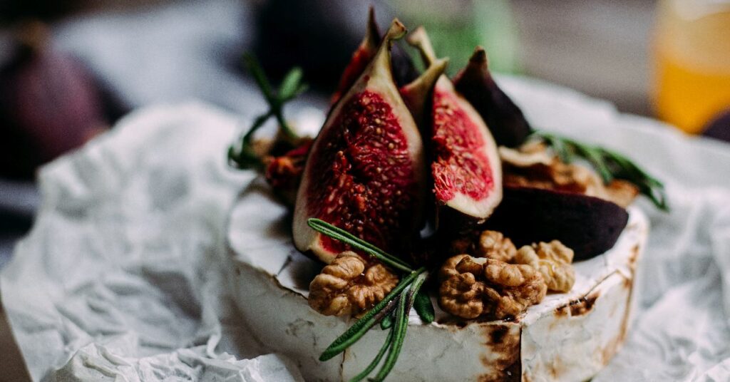 sütőben sült füge és camembert ízlésesen tálalva, zöldfűszerekkel, dióval