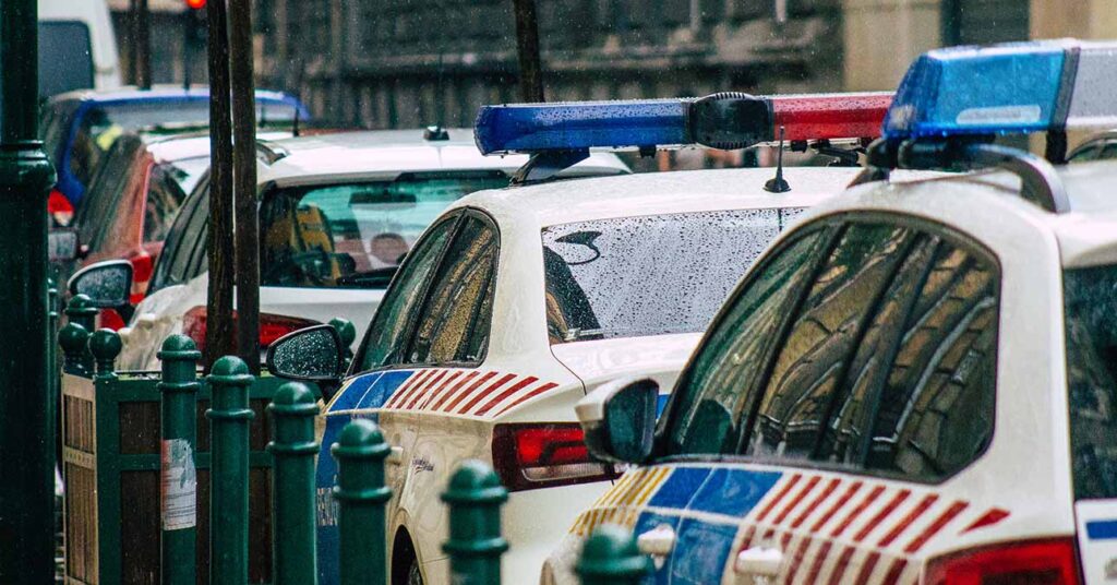 Rendőrautók parkolnak egy budapesti utcában esős napon