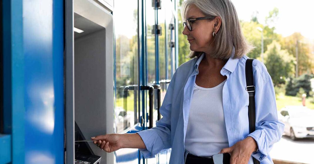 Középkorú nő ATM bankautomatát használ kártyával